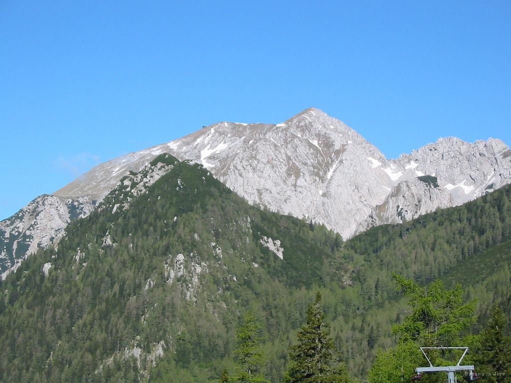 Slika_12.jpg - Bližnja špica poraščena z gozdom je Srednji vrh (1796 m), v ozadju pa Stol (2236 m) in levo vidna Prešernova koča na Stolu (2174 m).